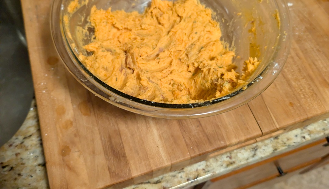 Mashed sweet potato dough in a glass bowl